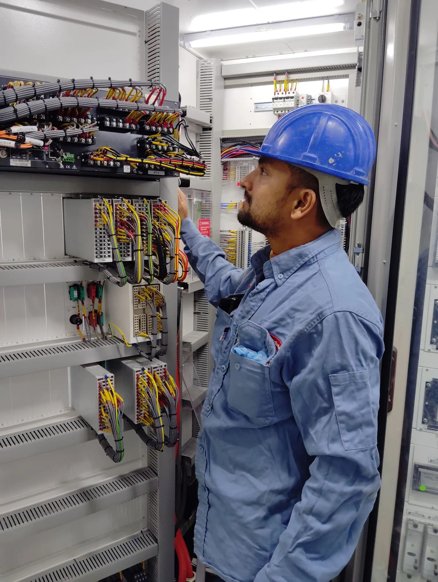Technician inspecting wiring inside a commercial electrical control cabinet