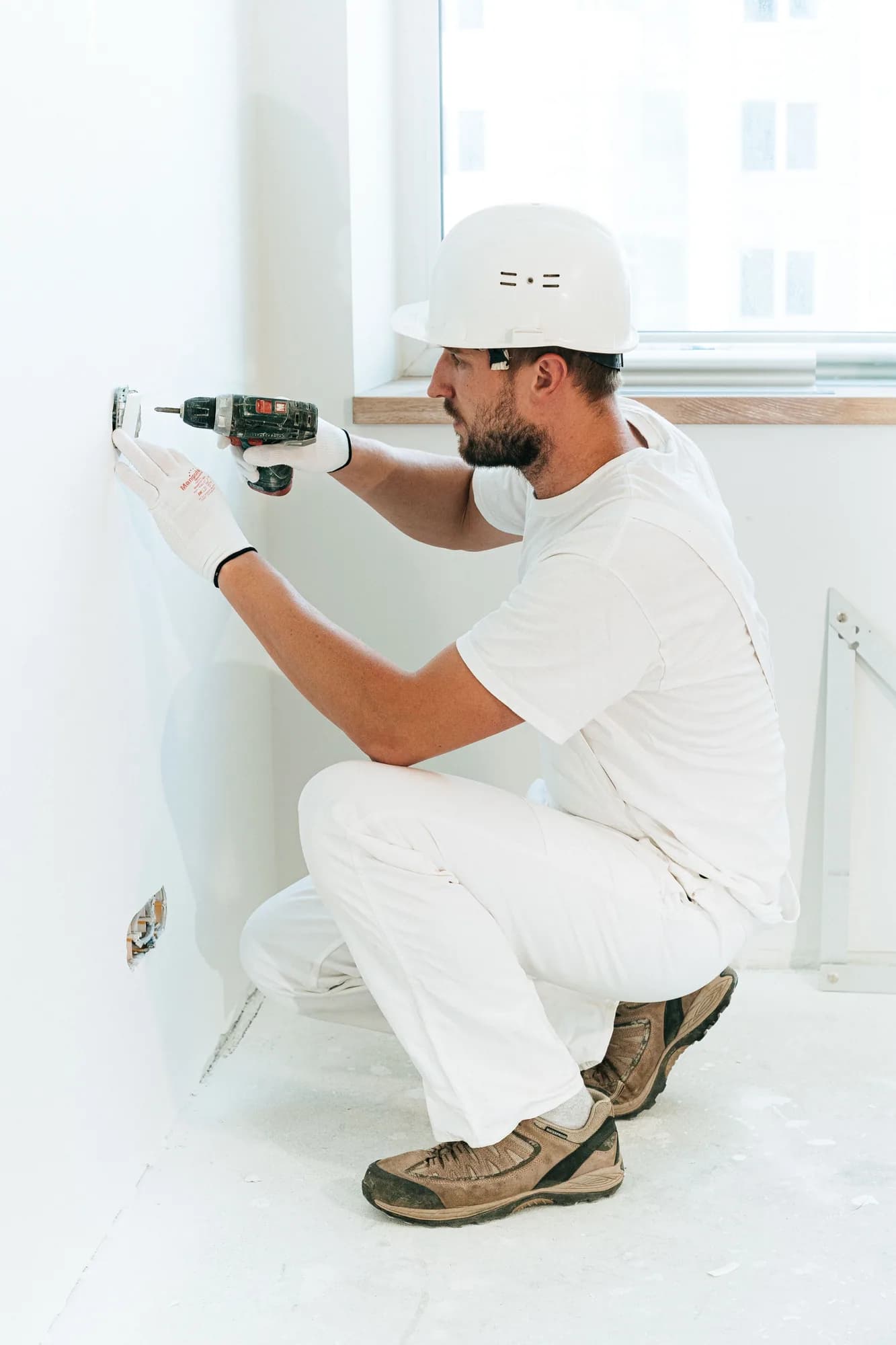 Worker carefully installing an electrical wall device in a finished room